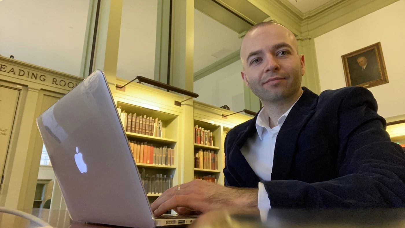 Fabjan Pepaj working on a laptop in a library